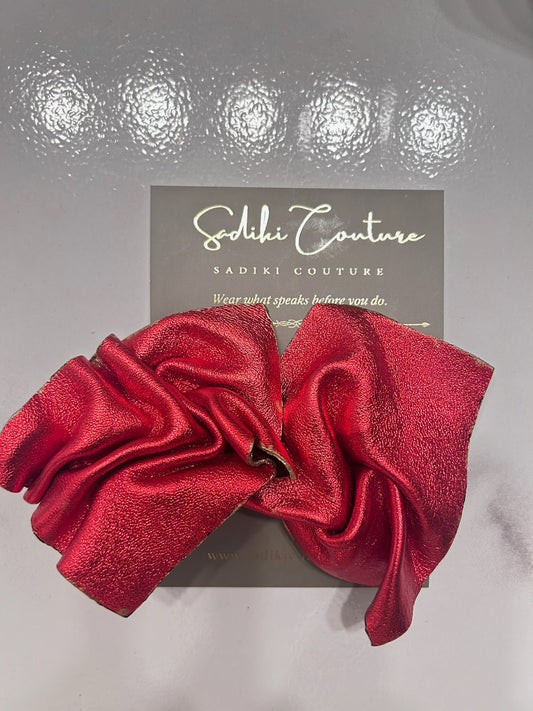 Red earrings with sculpted petal-like folds on a Sadiki Couture display card